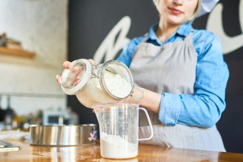 בחורה משתמשת בכוסות מדידה לצורך אפיית עוגה